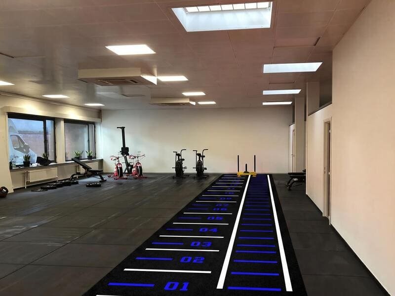 Heavy commercial gym sled being pushed over a durable SPU backed turf surface during a quality test